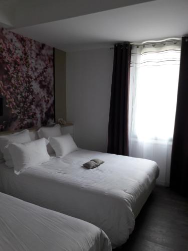 a bedroom with two beds and a window at Hôtel-Restaurant "Chez Carrière" in Aigues-Mortes