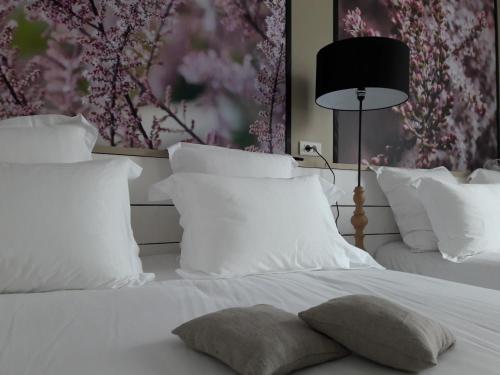 a white bed with white pillows and a black lamp at Hôtel-Restaurant "Chez Carrière" in Aigues-Mortes