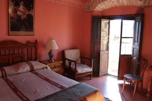 a bedroom with orange walls and a bed and a chair at Hotel El Real in Real de Catorce