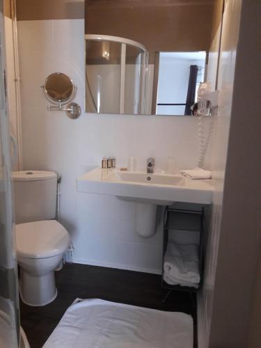 a bathroom with a sink and a toilet and a mirror at Hôtel-Restaurant "Chez Carrière" in Aigues-Mortes