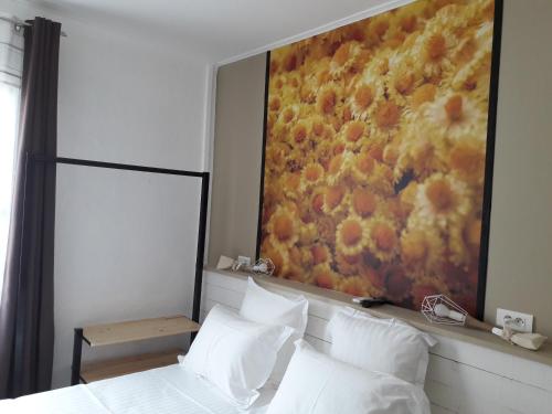 a bedroom with a painting of flowers on the wall at Hôtel-Restaurant "Chez Carrière" in Aigues-Mortes