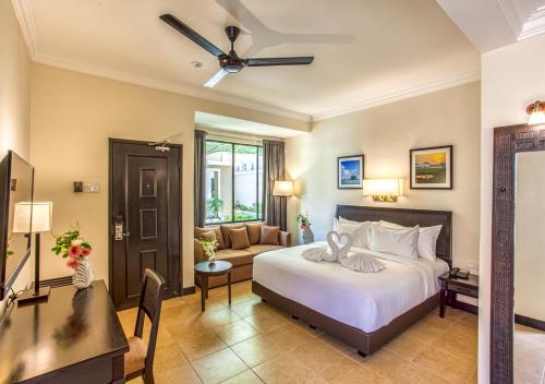a bedroom with a bed and a living room at Camar Resort Langkawi in Pantai Cenang
