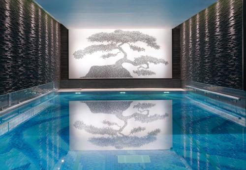a swimming pool with a bonsai art on the wall at The Langham London in London