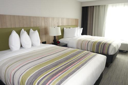 a hotel room with two beds and a window at Country Inn & Suites by Radisson, Lawrence, KS in Lawrence
