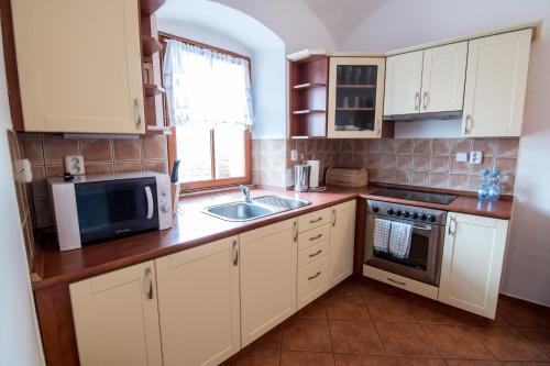 a kitchen with white cabinets and a sink and a microwave at Tylova Apartments in Kutná Hora