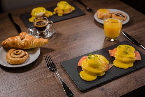 una mesa de madera con platos de comida y vasos de zumo de naranja en Westmead Hotel Bar & Restaurant, en Hopwood