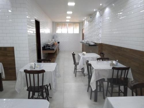 una sala da pranzo con tavoli e sedie bianchi in un ristorante di Hotel Imperial a Palmeira dos Índios