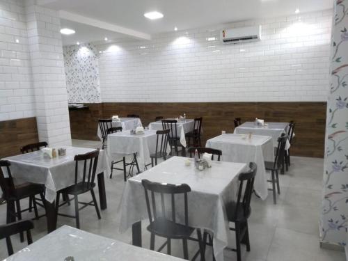 una sala da pranzo con tavoli e sedie bianchi di Hotel Imperial a Palmeira dos Índios