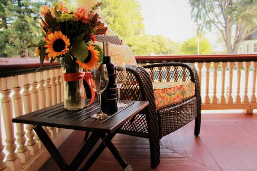 a table with two bottles and a vase of flowers on a porch at Cabernet House, an Old World Inn in Napa