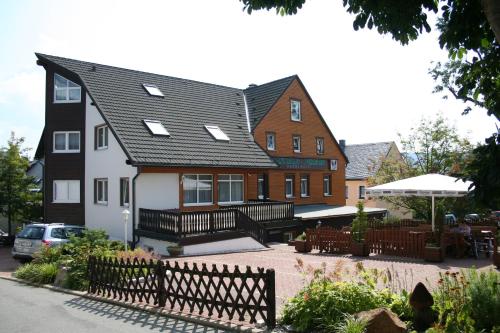 ein großes Haus mit einem Zaun davor in der Unterkunft Gasthaus-Pension Herberger in Kurort Oberwiesenthal