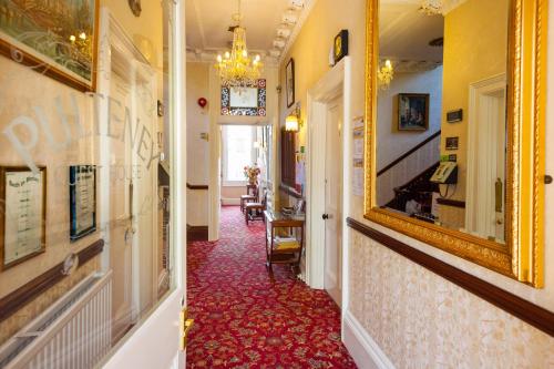 a hallway with a mirror on the wall and a hallway with a red carpet at Pulteney House in Bath