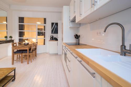 a kitchen with white cabinets and a wooden table at Bordeaux Village Blaye in Blaye