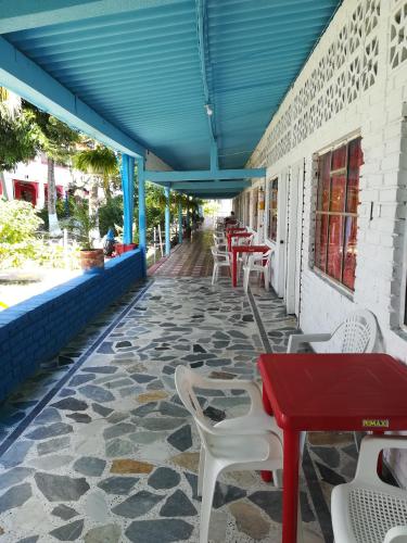 a patio with tables and chairs and a blue roof at Hotel Sael in Tocaima