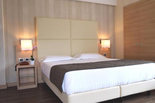 a bedroom with a large white bed with two lamps at Hotel Continental in Taormina