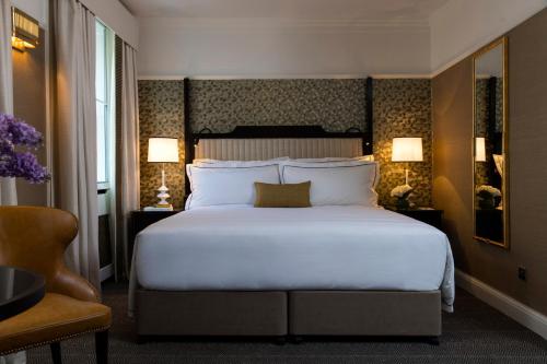 um quarto com uma grande cama branca e 2 candeeiros em The Academy - Small Luxury Hotels of the World em Londres