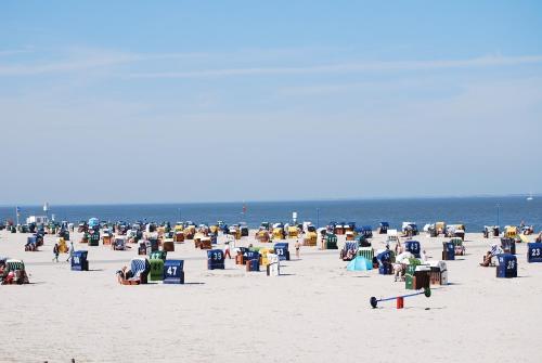 a group of people sitting in chairs on the beach at Hotel Peters in Neuharlingersiel