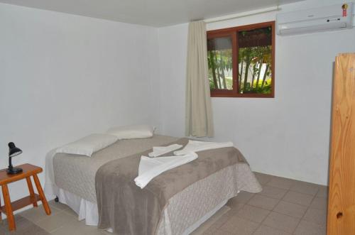 a bedroom with a bed with towels on it at Pousada Louise in Pinheira