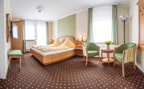 a bedroom with a bed and two chairs and a table at Hotel Peters in Neuharlingersiel