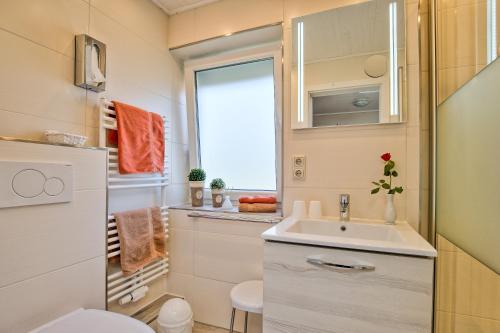 a small bathroom with a sink and a window at Hotel Peters in Neuharlingersiel