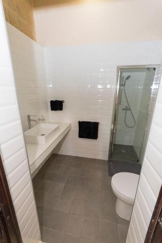 a bathroom with a toilet and a sink and a shower at The Burrow Guest House in Tarxien
