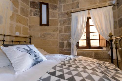 a bedroom with a bed with a rabbit on a pillow at The Burrow Guest House in Tarxien