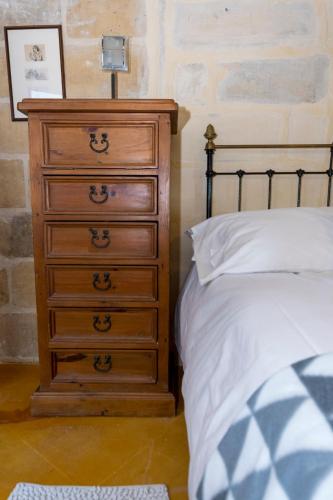a bedroom with a wooden dresser and a bed at The Burrow Guest House in Tarxien