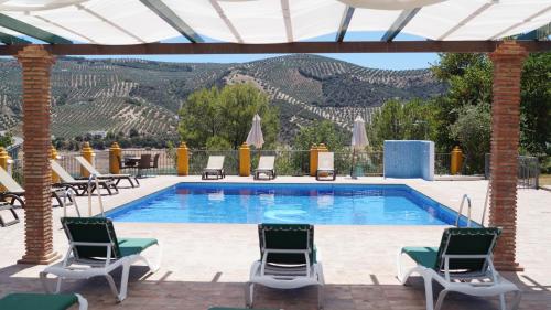 a pool with chairs and a view of the mountains at Caserio de Iznájar in Iznájar