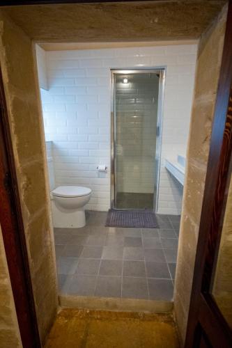 a bathroom with a toilet and a glass shower at The Burrow Guest House in Tarxien