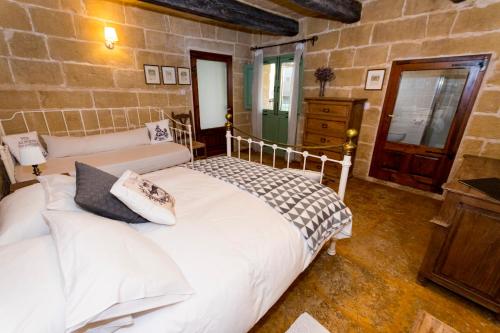 a bedroom with a white bed and a stone wall at The Burrow Guest House in Tarxien