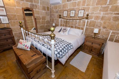 a bedroom with a bed and a stone wall at The Burrow Guest House in Tarxien