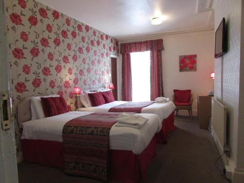 um quarto de hotel com duas camas e uma janela em Holliers Hotel em Shanklin