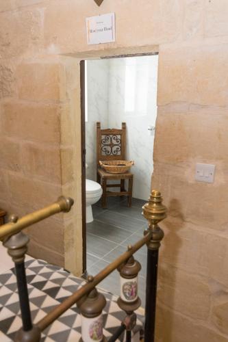 a bathroom with a toilet and a chair at The Burrow Guest House in Tarxien