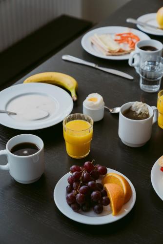 a table with plates of fruit and cups of coffee at 2Home Hotel Gävle in Gävle