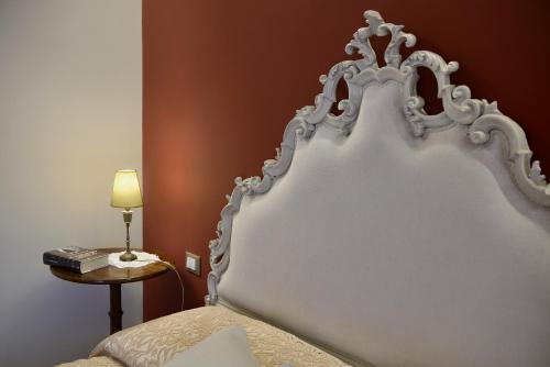 a white headboard of a bed with a lamp and a table at Villa Le Facezie B&B in Terranuova Bracciolini