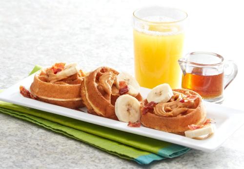 a plate with waffles and bananas and a glass of orange juice at Comfort Suites Fort Lauderdale Airport & Cruise Port in Dania Beach