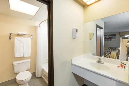 a bathroom with a sink and a toilet and a mirror at Super 8 by Wyndham Wichita North in Wichita