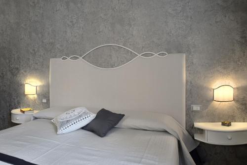 a bedroom with a white bed with two tables and two lamps at Villa Le Facezie B&B in Terranuova Bracciolini