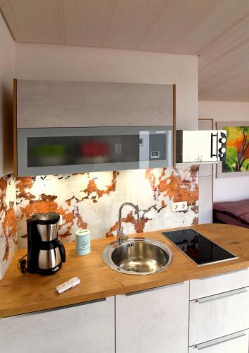 a kitchen counter with a sink and a coffee maker at PETIT-CHALET AM HAINER SEE in Rötha