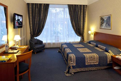 a hotel room with a bed and a desk at Grand Hotel Ukraine in Dnipro
