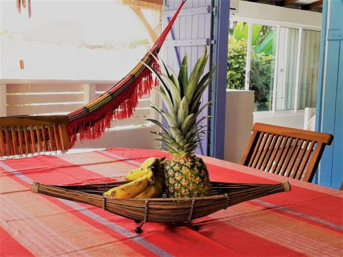 a pineapple and a bunch of bananas in a basket on a table at Villa BonBon Siwo in Le Diamant