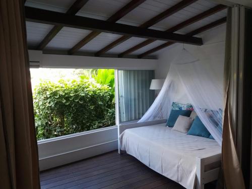 a bedroom with a white bed on a balcony at Villa BonBon Siwo in Le Diamant