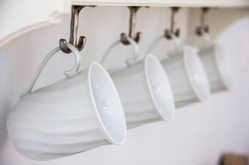 a group of white mugs hanging from a rack at Aegli Apartments in Symi