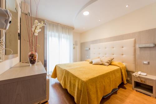 a bedroom with a bed with a yellow bedspread at Hotel Atlantic in Bellaria-Igea Marina