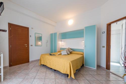 een slaapkamer met een bed met een gele sprei bij Hotel Atlantic in Bellaria-Igea Marina