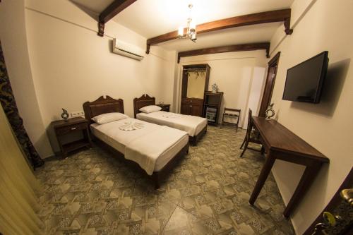 a hotel room with two beds and a television at Hotel Mary's House in Selcuk