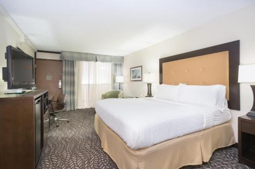 een hotelkamer met een groot bed en een flatscreen-tv bij Holiday Inn Little Rock-Airport-Conference Center, an IHG Hotel in Little Rock