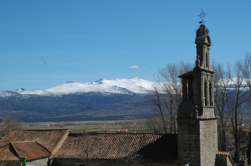 a clock tower with snow covered mountains in the background at Casa Rural Reposo de Afanes in Muñogalindo