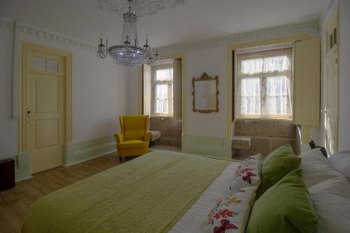 a bedroom with a large bed and a yellow chair at HC Villa Douro in Vila Nova de Gaia