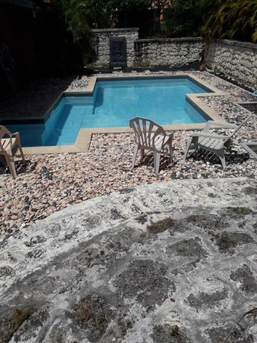 a swimming pool with two chairs and a bench next to it at Le studio de Véro in Sainte-Anne