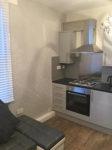 Il comprend une petite cuisine équipée d'une cuisinière et d'un canapé. dans l'établissement Modern Luxury Central Apartment, à Birmingham